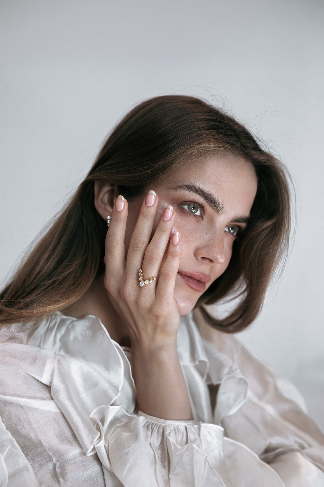 Portrait of a model wearing the J’ador V-Bloom ring by Presiada, a delicate V-shaped design crafted in 18K gold and adorned with oval diamonds. This piece exudes romantic elegance, perfect for special occasions or everyday grace. Available in natural or lab-grown diamonds.