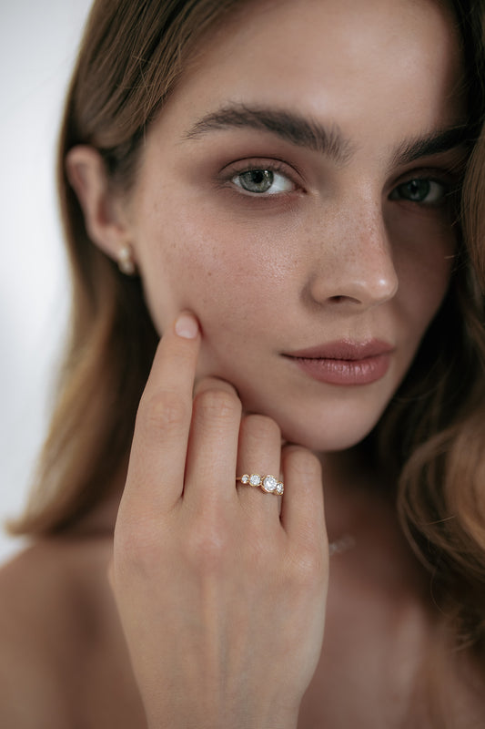 Close-up of a model wearing the La Belle engagement ring by Presiada, crafted in 18K gold. The ring features five round diamonds set in perfect harmony, blending classic elegance with a modern twist. A unique, made-to-order piece, perfect for those seeking a timeless and personalized engagement ring.