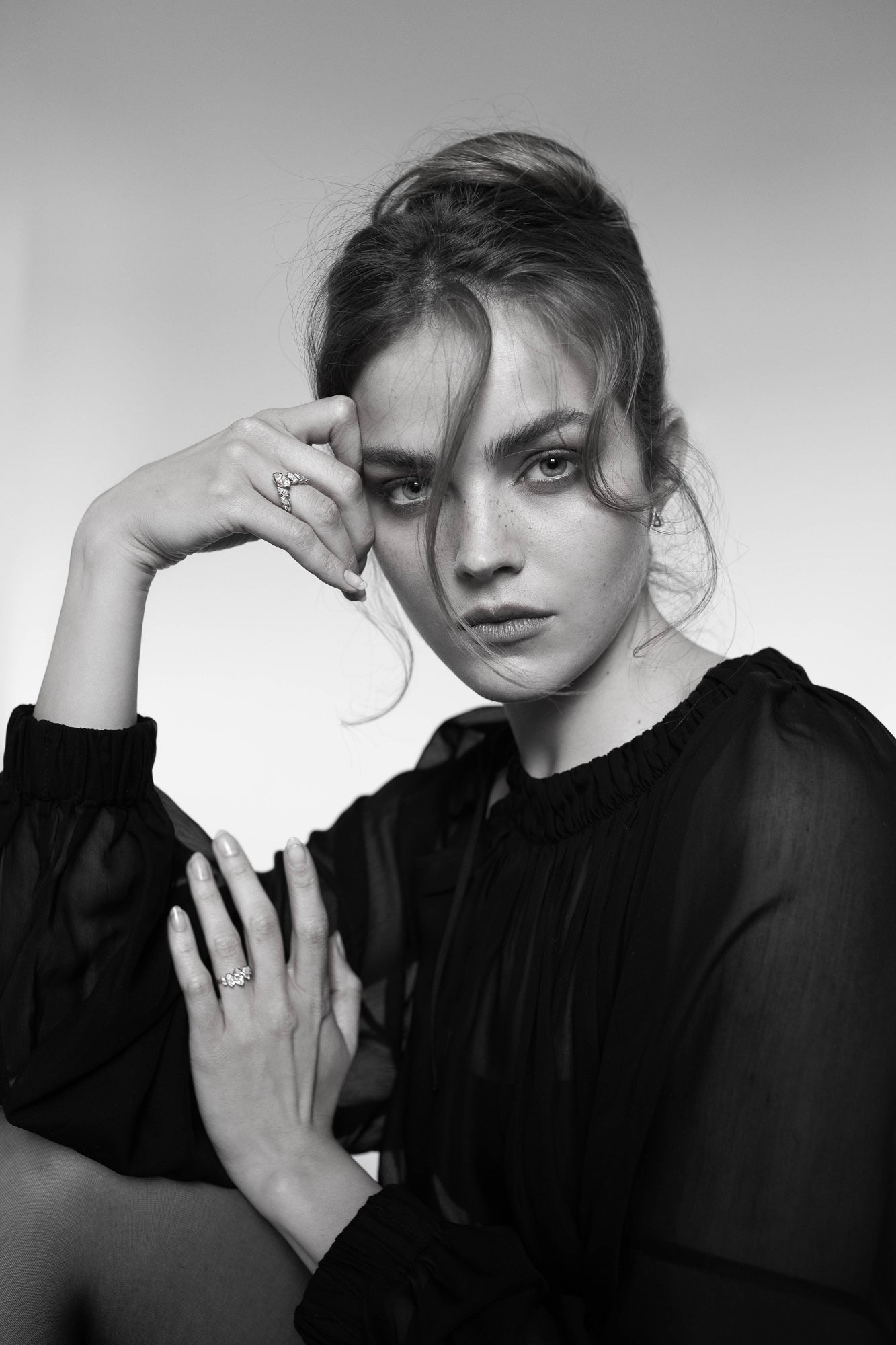 Black and white portrait of a model wearing Presiada's VIVID 18K gold earrings, paired with two elegant engagement rings, J'ador V Flam and La Divine. These exquisite designs feature dazzling diamonds and belong to the Sensation Collection, showcasing timeless luxury and modern artistry.