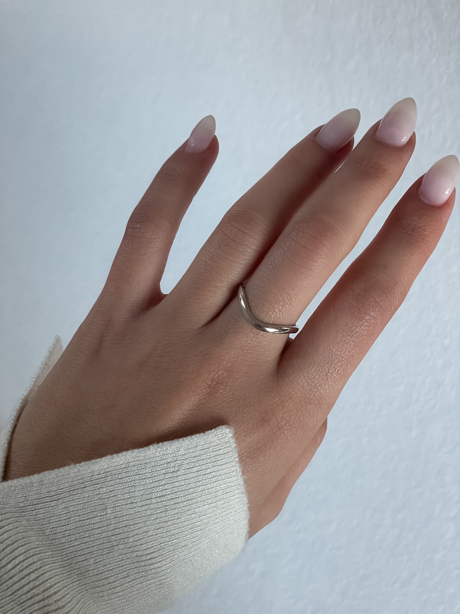 A model showcasing the Wave Ring by Presiada, a sculptural twisted band crafted in 14K or 18K gold. This elegant yet modern wedding band perfectly complements engagement rings or stands alone as a timeless statement.