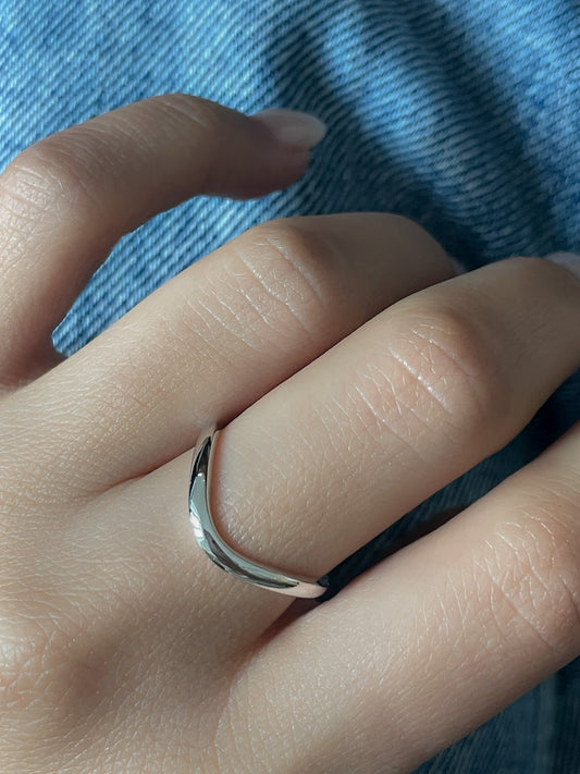 A model showcasing the Wave Ring by Presiada, a sculptural twisted band crafted in 14K or 18K gold. This elegant yet modern wedding band perfectly complements engagement rings or stands alone as a timeless statement.