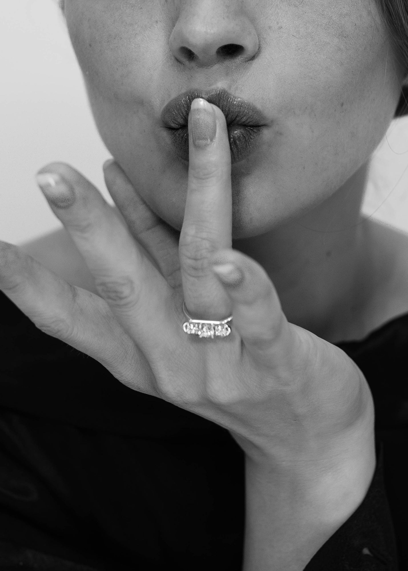 Black and white Close-up of a model wearing the Élevé ring by Presiada, crafted in 18K gold. The Élevé ring features a stunning floating frame diamond design with a central diamond and two side accents, offering modern sophistication and timeless elegance. Part of the Sensation Collection, it is available in natural or lab-grown diamonds to suit your preferences.