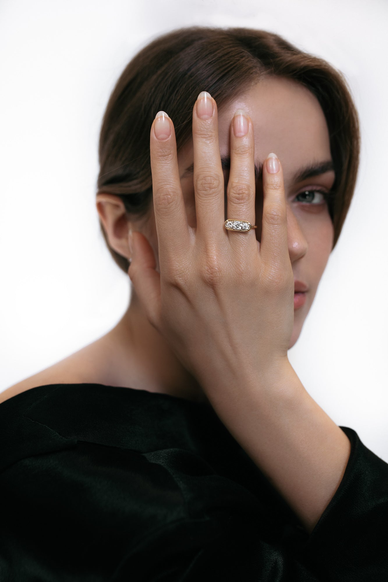 Close-up of a model wearing the Élevé ring by Presiada, crafted in 18K gold. The Élevé ring features a stunning floating frame diamond design with a central diamond and two side accents, offering modern sophistication and timeless elegance. Part of the Sensation Collection, it is available in natural or lab-grown diamonds to suit your preferences.