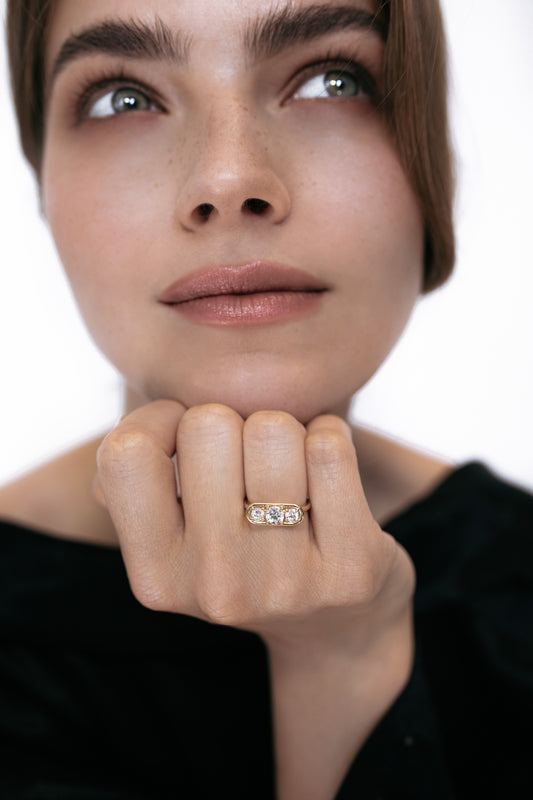 Close-up of a model wearing the Élevé ring by Presiada, crafted in 18K gold. The Élevé ring features a stunning floating frame diamond design with a central diamond and two side accents, offering modern sophistication and timeless elegance. Part of the Sensation Collection, it is available in natural or lab-grown diamonds to suit your preferences.
