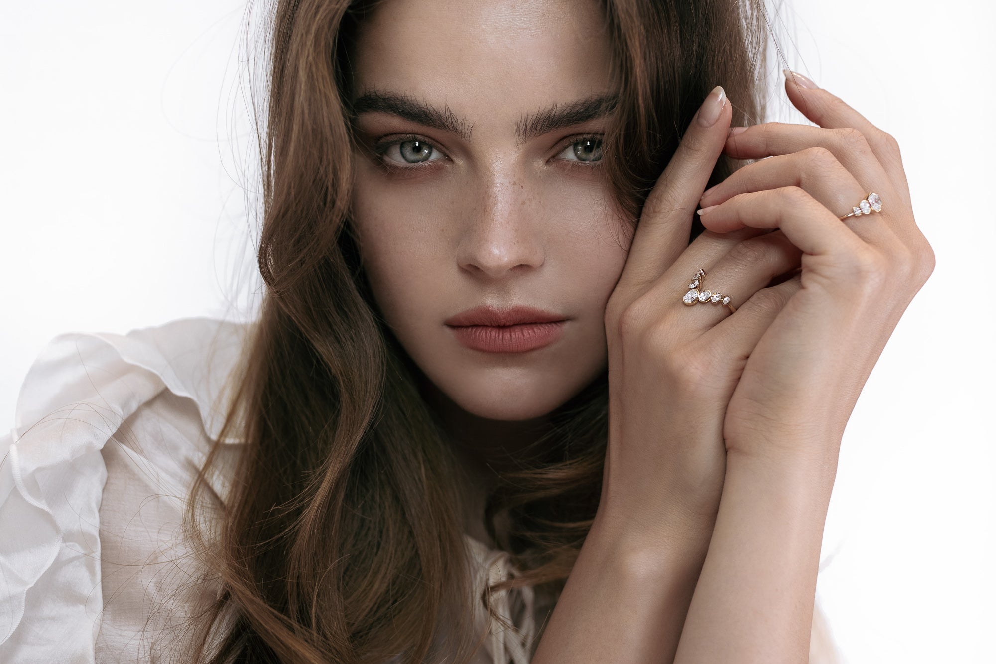 Artistic shot of a model showcasing two Presiada rings: the J’ador V-Bloom ring, symbolizing growth and grace with its V shape and oval diamonds, and the La Blossom ring, featuring a central diamond surrounded by five oval diamonds for a distinctive and elegant design. Crafted in 18K gold, both rings are customizable with natural or lab-grown diamonds.