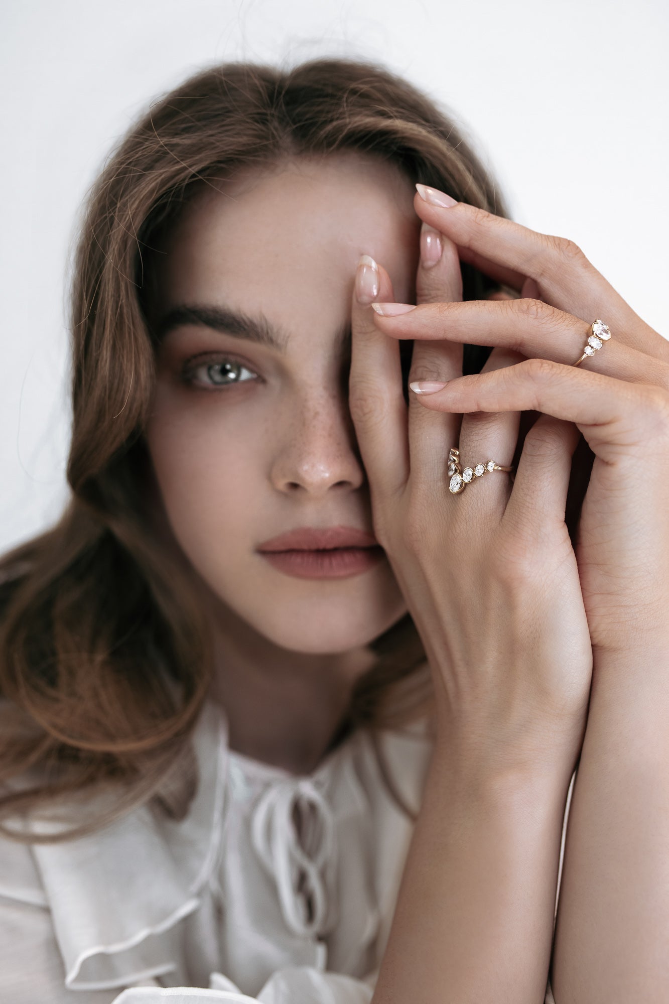 Elegant shot of a model wearing two Presiada rings: the J’ador V-Bloom ring, featuring a V shape with stunning oval diamonds, and the La Blossom ring, crafted in 18K gold with a unique arrangement of five oval diamonds around a central diamond. Both rings reflect timeless beauty and intricate craftsmanship, available in natural or lab-grown diamonds.