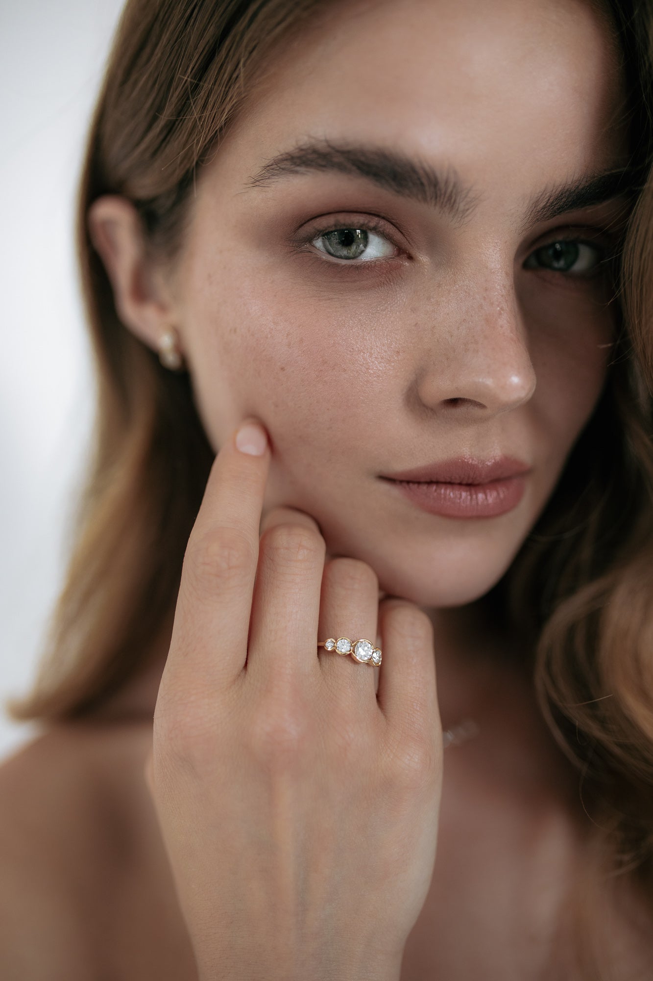 Close-up of a model wearing the La Belle engagement ring by Presiada, crafted in 18K gold. The ring features five round diamonds set in perfect harmony, blending classic elegance with a modern twist. A unique, made-to-order piece, perfect for those seeking a timeless and personalized engagement ring.