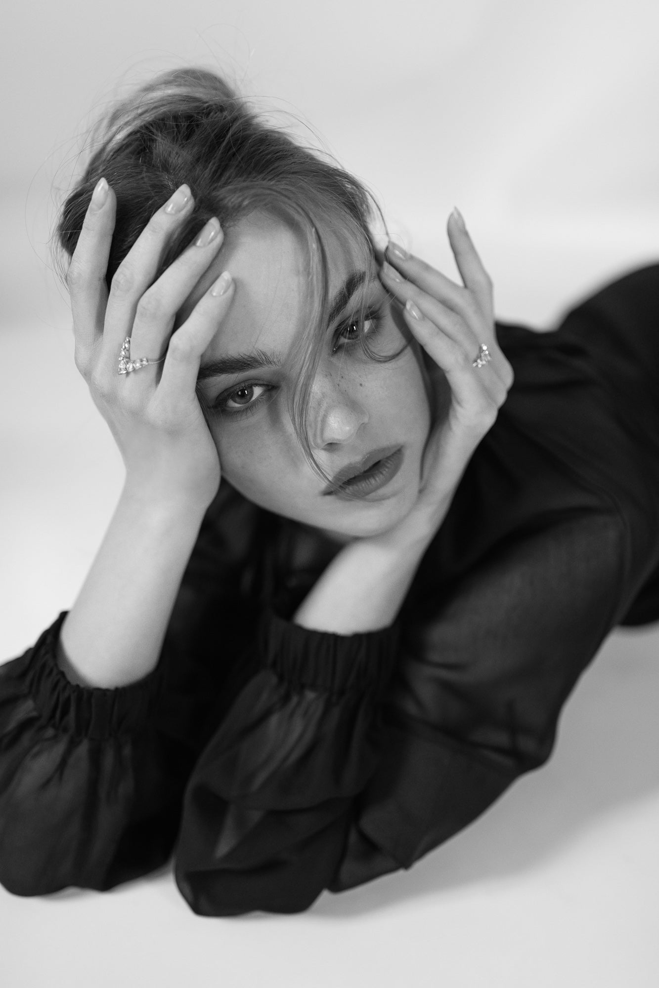 Black and white portrait of a model wearing Presiada's VIVID 18K gold earrings, paired with two elegant engagement rings, J'ador V Flam and La Divine. These exquisite designs feature dazzling diamonds and belong to the Sensation Collection, showcasing timeless luxury and modern artistry.