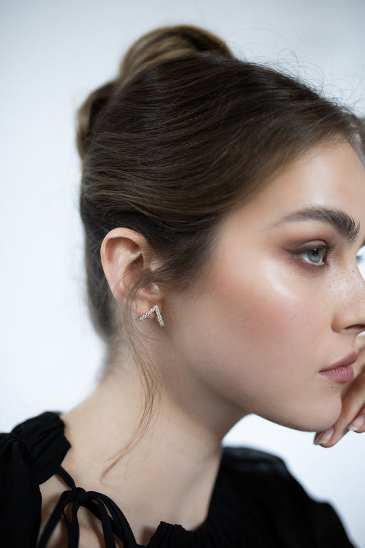 Close-up of Presiada’s Vivid Earrings in 18K gold, featuring a bold V-shaped design set with 0.75 carats of dazzling diamonds. The earrings sit elegantly at an angle on the ears and are available with natural or lab-grown diamonds. Part of the Sensation Collection, these earrings highlight modern design and impeccable craftsmanship, perfect for making a sparkling statement.