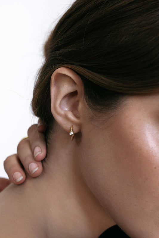close up Side profile of a model wearing the Élany Hoops in 18k yellow gold, featuring delicate marquise diamonds totaling 0.1 ct. These earrings offer a modern twist on classic elegance, perfect for everyday sophistication.